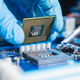 A technician lays down a computer chip into a motherboard.